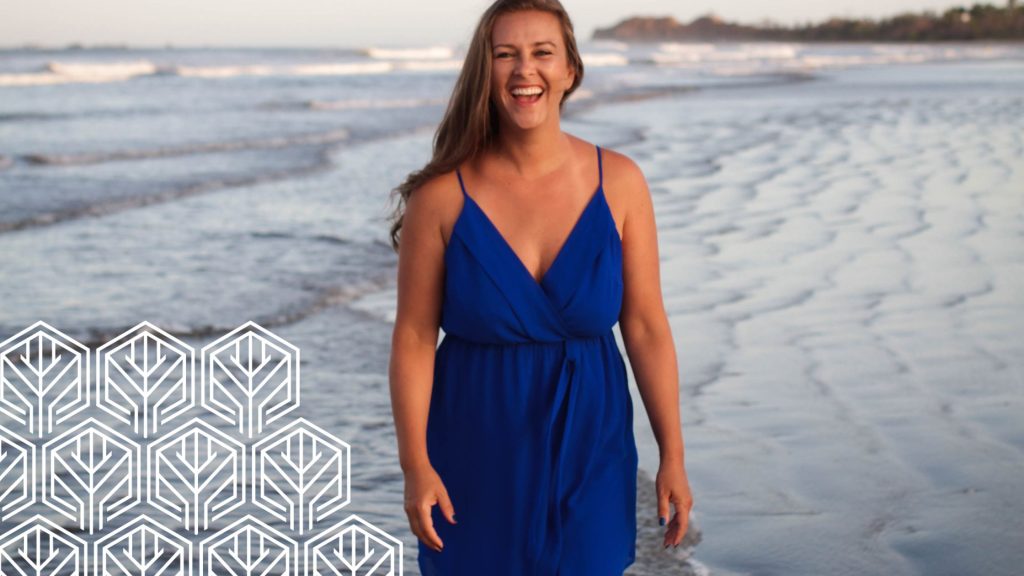 an image of a long-haired woman smiling in her blue dress on the beach