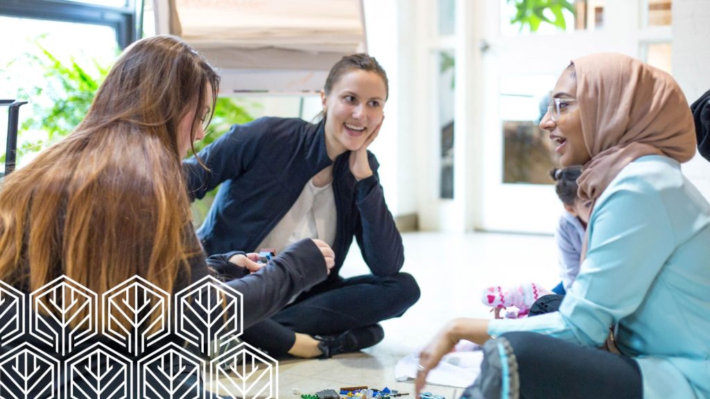 Three woman squatting on the floor talking to each other