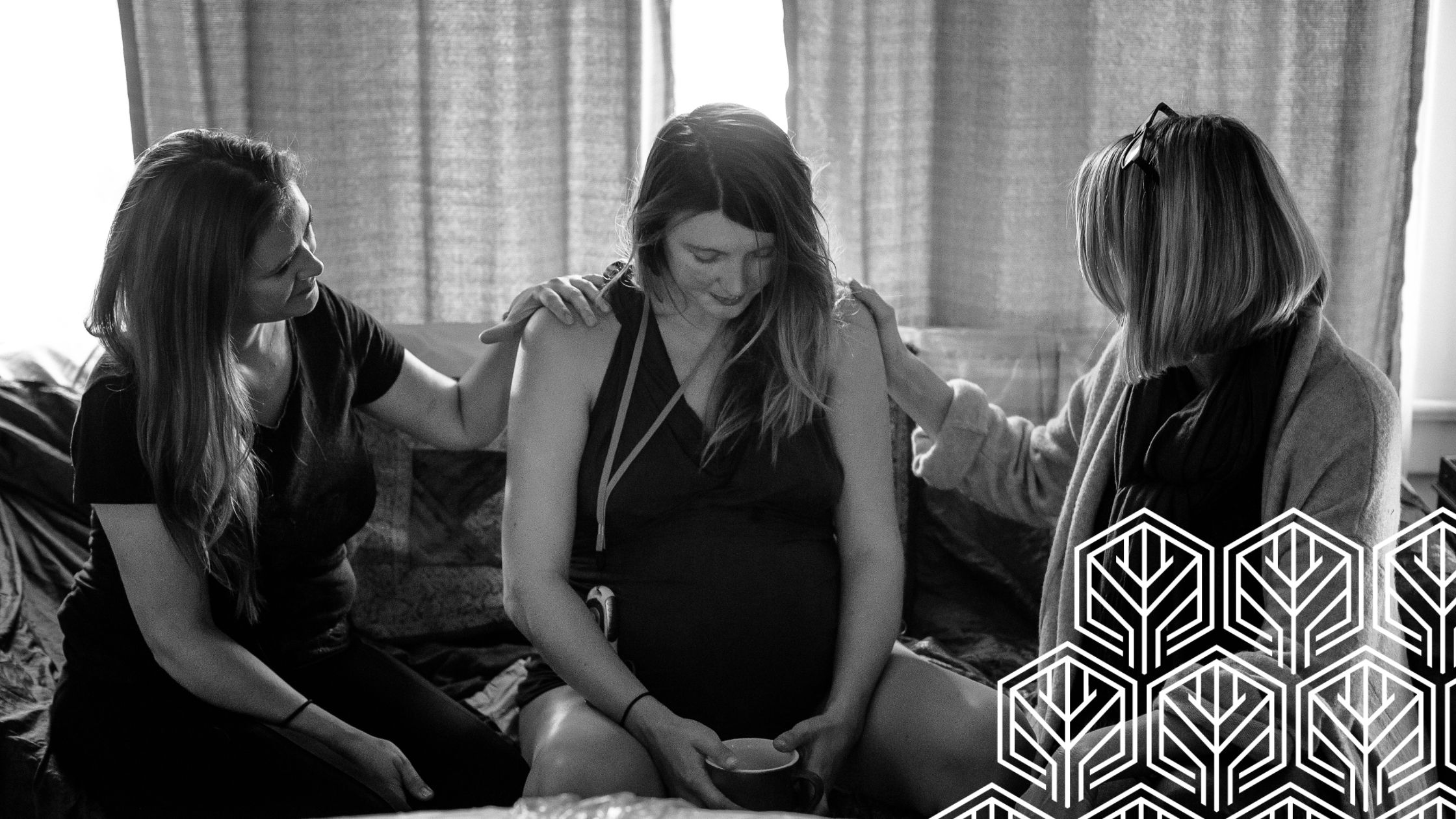 a pregnant woman holding a cup of water sitting between two doula